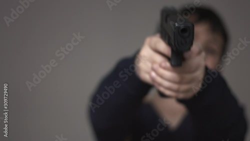 Blurred anonymous young boy silhouette pointing a nine millimeter toy gun perfect replica at the camera and shooting