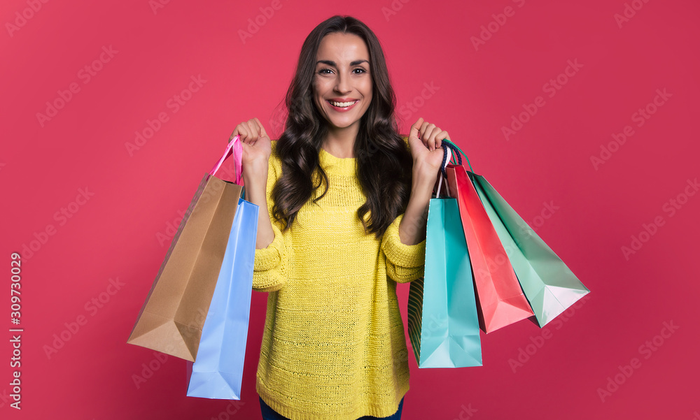 Not just window shopping. Perfect happy woman in a casual outfit is holding several shopping paper bags in her hands, showing them to the camera. Not just window shopping. Perfect happy woman in a casual outfit is holding several shopping paper bags in her hands, showing them to the camera.