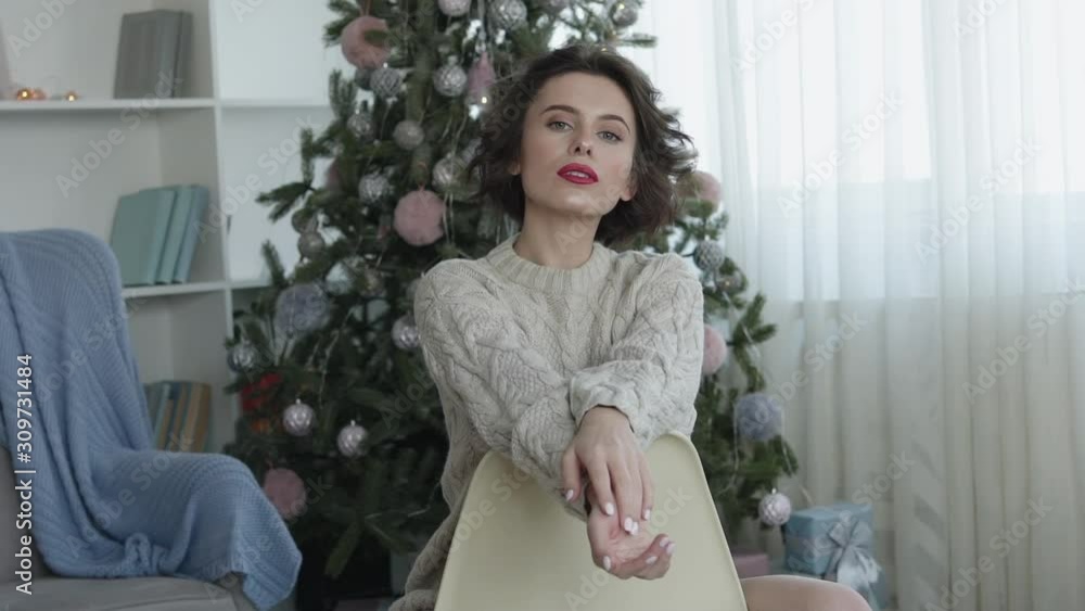 Portrait of pretty woman leaned on chair at christmas tree Portrait of pretty woman leaned on chair at christmas tree