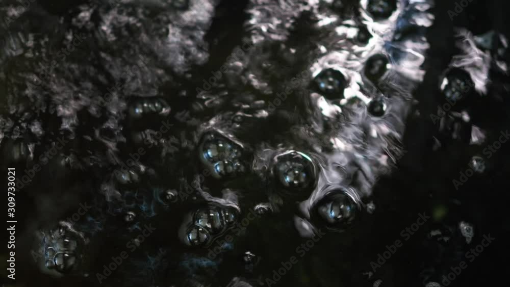 Bubbles floating on the black water surface. Black water ripples. Bubbles floating on the black water surface. Black water ripples.
