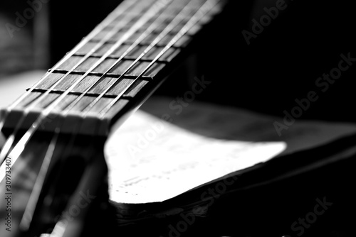 A fragment of an acoustic guitar lit by the sun. Black and white