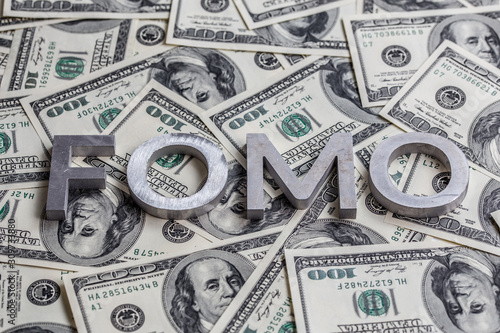 Quadro su tela The word FOMO laid with aluminium letters on the US dollar banknotes background