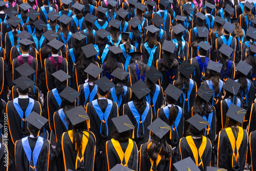 Rear view and soft selective focus of the graduates in the graduation commencement ceremony recieving diploma degree certificate.