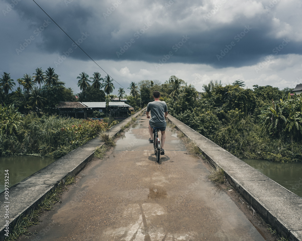 Cycling into the rain at Don Det Island 