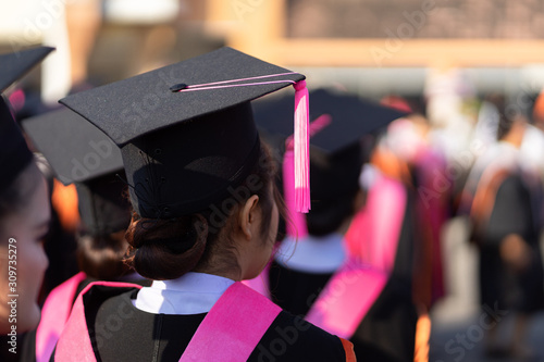 Rear view and soft selective focus of the graduates in the graduation commencement ceremony recieving diploma degree certificate.