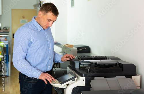 Worker is printing a file, document in the office room