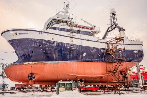 Fishing ships hulls in dockyard on maintenance during the winter time, port of Nuuk, Greenland