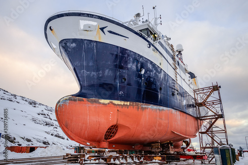 Fishing ships hulls in a dockyard on maintenance during the winter time, port of Nuuk, Greenland