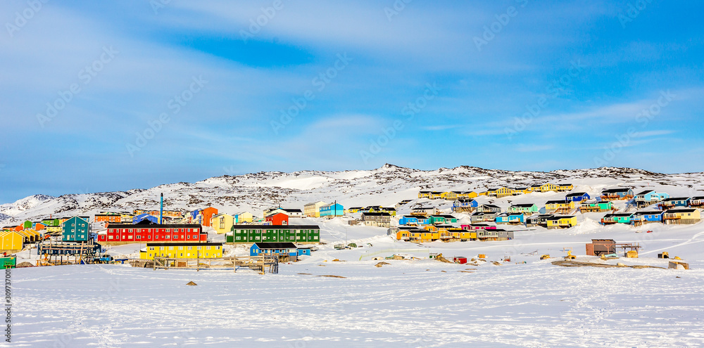 Arctic city center panorama with colorful Inuit houses on the rocky hills covered in snow, Ilulissat, Avannaata municipality, Greenland