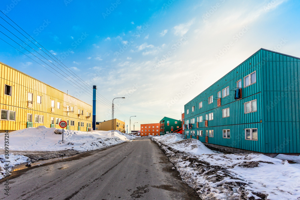 Muddy road with snow and living blocks with long low buildings in  Ilulissat city, Greenland