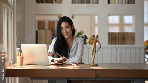 Obraz na plátně Portrait shot young woman looking at camera in home office.