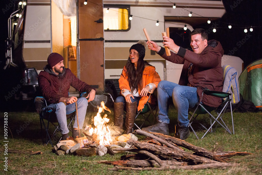 Group of close friends warming up around camp fire Group of close friends warming up around camp fire