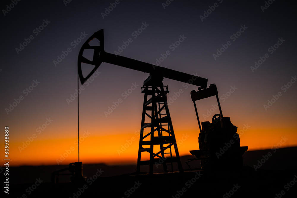 Creative artwork decoration. Oil pump and oil refining factory at sunset. Energy industrial concept. Selective focus.