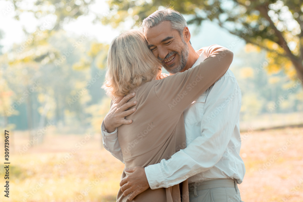 Happy senior couple hugging in park in love and romantic Happy senior couple hugging in park in love and romantic
