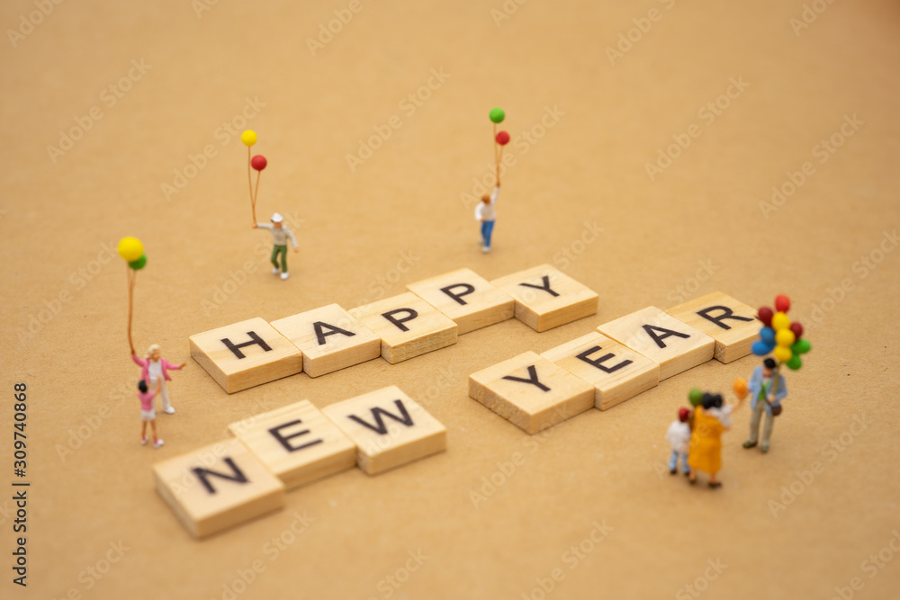 Obraz premium Family Miniature people standing with wood word Happy new year using as background Universal day concept and Happy new year concept with copy space for your text or design.