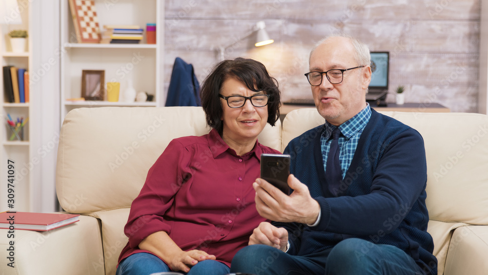 Obraz premium Old man and woman having a video call using their smartphone