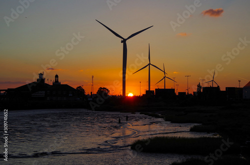 Silhouette of Wind power plant with propellers against setting sun twilight sky at River Thames photo