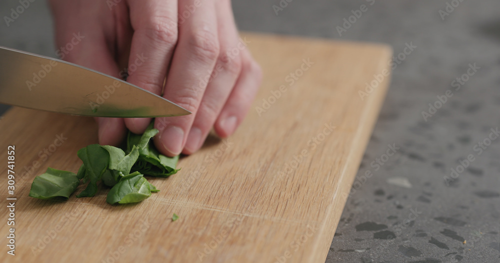 man chopping fresh spinach leaves on oak cutting board man chopping fresh spinach leaves on oak cutting board