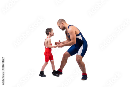 A  wrestler boy in a sports tights wrestles with an adult male wrestler on a white isolated background. The concept of child power and martial arts training. Teaching children Greco-Roman wrestling © Виталий Сова