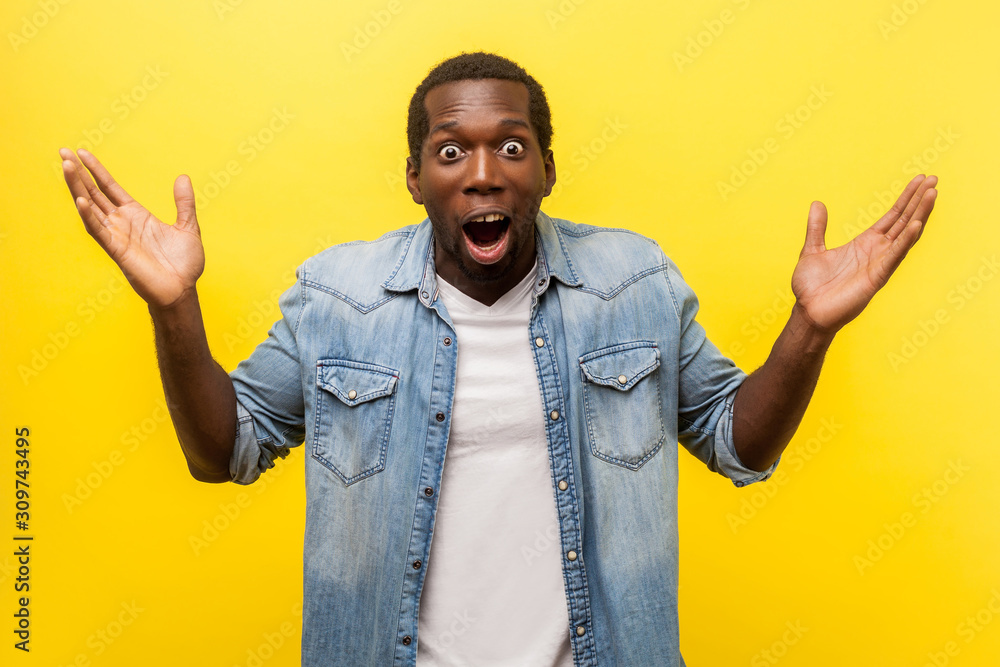 Wow, it's unbelievable! Portrait of bewildered shocked man in denim casual shirt staring at camera with widely open mouth and big eyes, raising arms in amazement. indoor studio shot isolated on yellow Wow, it's unbelievable! Portrait of bewildered shocked man in denim casual shirt staring at camera with widely open mouth and big eyes, raising arms in amazement. indoor studio shot isolated on yellow