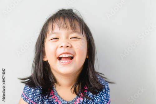 Happy Little asian girl child showing front teeth with big smile and laughing: Healthy happy funny smiling face young adorable lovely female kid.Joyful portrait of asian elementary school student. photo