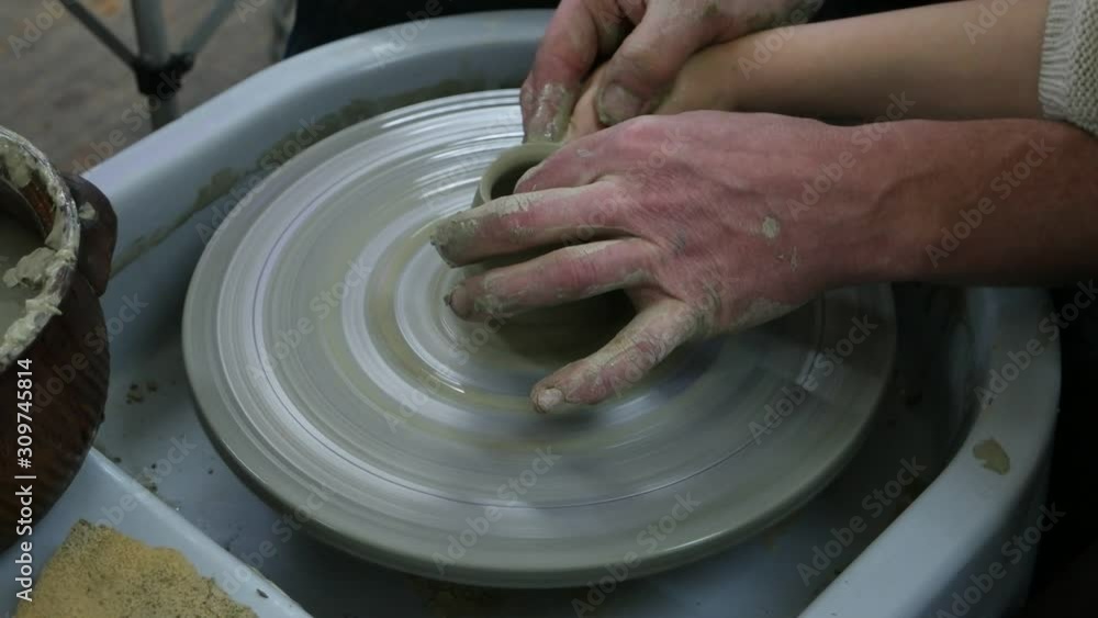 Adult man and child work with clay on a potter's wheel Adult man and child work with clay on a potter's wheel