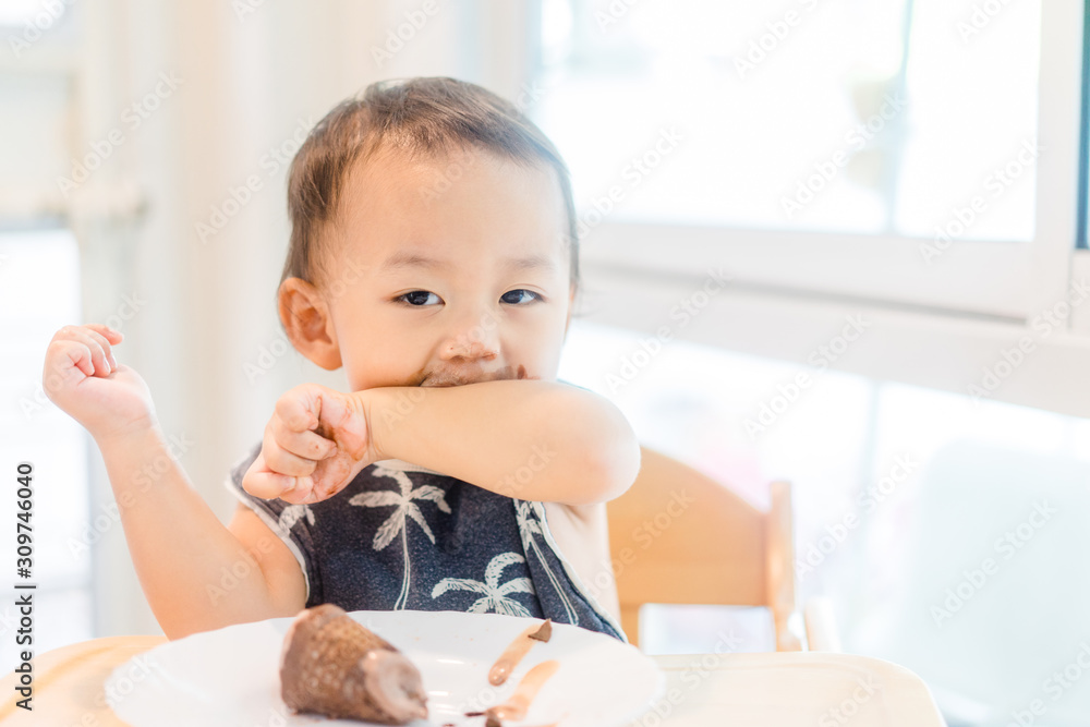 Happy Little asian baby boy eating chocolate soft cream or ice cream cone at home in summer Happy Little asian baby boy eating chocolate soft cream or ice cream cone at home in summer