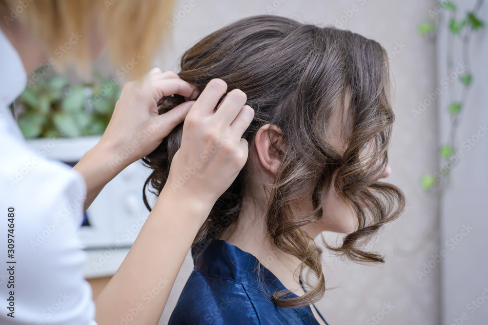 Fototapeta premium Hairdresser makes the wedding hairstyle the bride
