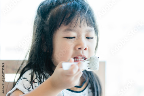 Little asian girl don't want to eat dragon fruit she hate every fruits.bored face bored food.5 years old girl does not want to eat her healthy foods