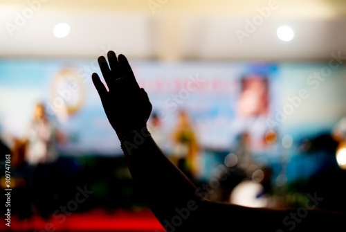 Silhouette photo of Hands Christian worship God together in Church hall in front of music stage.raised hand and praise the LORD.Music concert background.