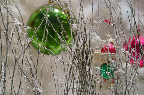 Photography of conceptual New Year decoration. Green and pink glass balls among artificial snow covered tree twigs. Theme of Christmas  festive mood. Suitable for posters  greeting cards  template