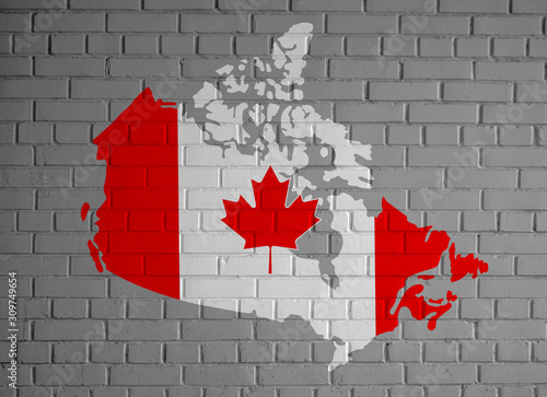 Canada map country silhouette in national Canadian flag colors and with maple leaf on the gray painted brick wall background texture.