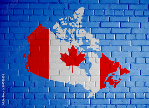 Canada map country silhouette in national Canadian flag colors and with maple leaf on the blue metal gradient painted brick wall background texture.