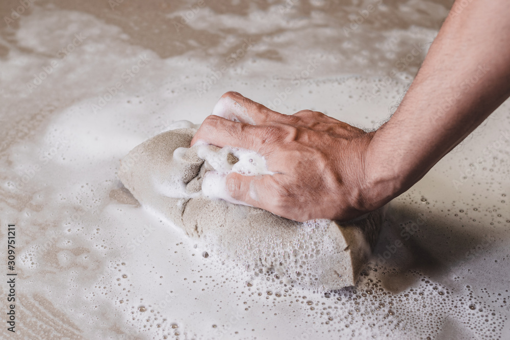 Fototapeta premium Men's hands are using a sponge cleaning the tile floor.