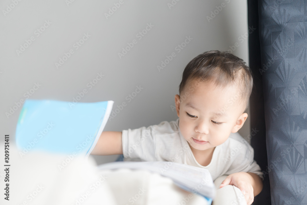 2 years little asian toddler boy in white t-shirt reading bible picture story for kid in the morning.Hands holding on a Holy Bible in bed room concept for Education bible study, faith and religion. 2 years little asian toddler boy in white t-shirt reading bible picture story for kid in the morning.Hands holding on a Holy Bible in bed room concept for Education bible study, faith and religion.