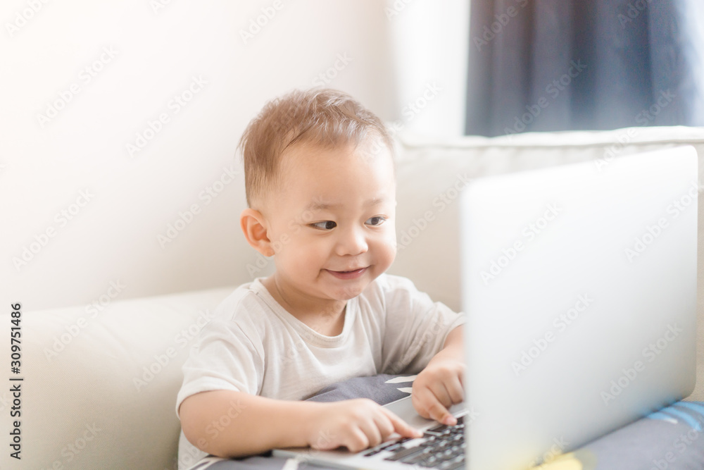 Portrait of a little toddler boy watching laptop and exciting face.Little asian boy child with laptop computer or notebook in living room at home.E Learning, Shopping online concept. Portrait of a little toddler boy watching laptop and exciting face.Little asian boy child with laptop computer or notebook in living room at home.E Learning, Shopping online concept.