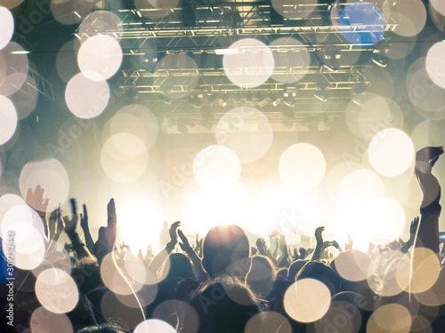 Принти на полотні Photo of a concert hall with people silhouettes clapping in front of a big stage lit by spotlights