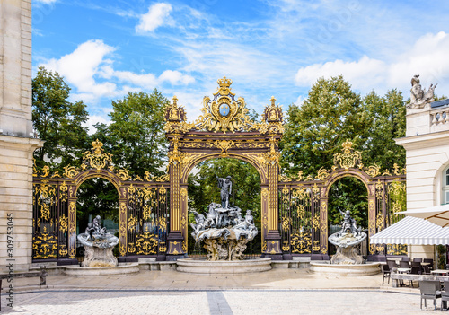 The fountain of Neptune in the Rococo style and the gilded wrought iron portico in the north-west corner of the Stanislas square in Nancy, France. photo