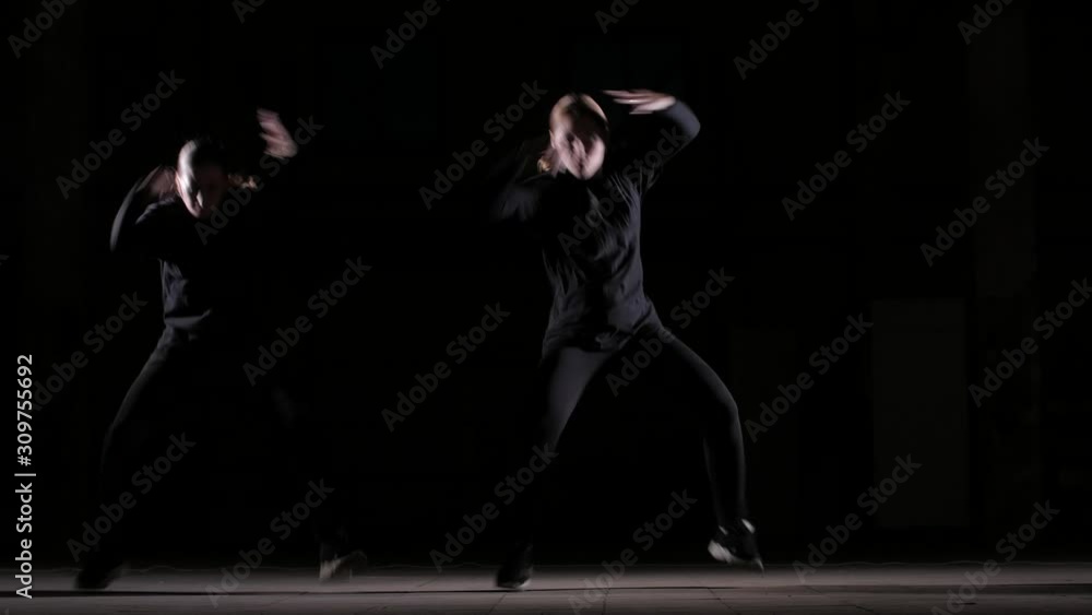 duet of young beautiful women dancing hip hop, street dancing on a black background in the studio, isolated duet of young beautiful women dancing hip hop, street dancing on a black background in the studio, isolated