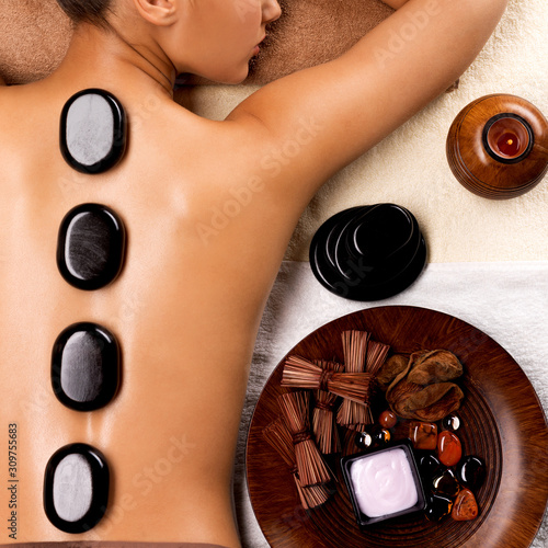 Young woman getting hot stone massage in spa salon.
