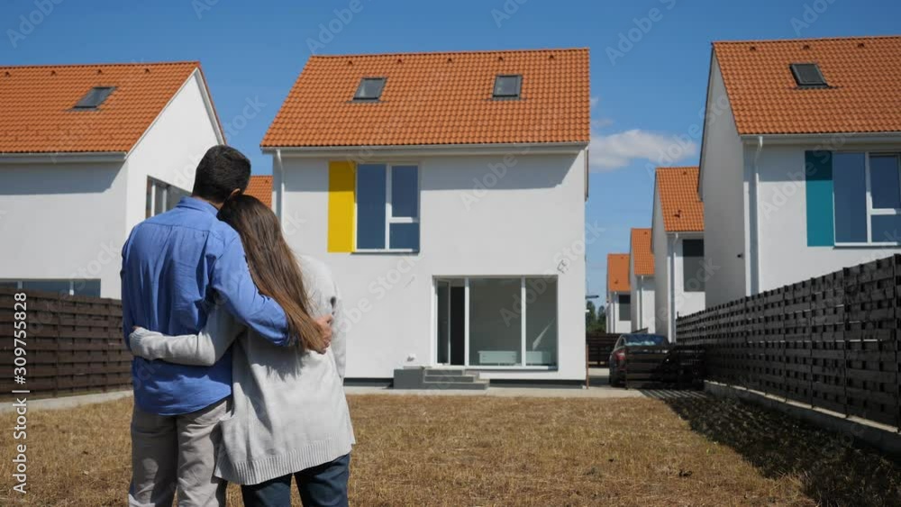 Happy couple admire their new house from the yard Happy couple admire their new house from the yard