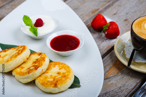 Traditional breakfast with coffee and cheesecakes, cottage cheese pancakes on a plate with syrup and jam.