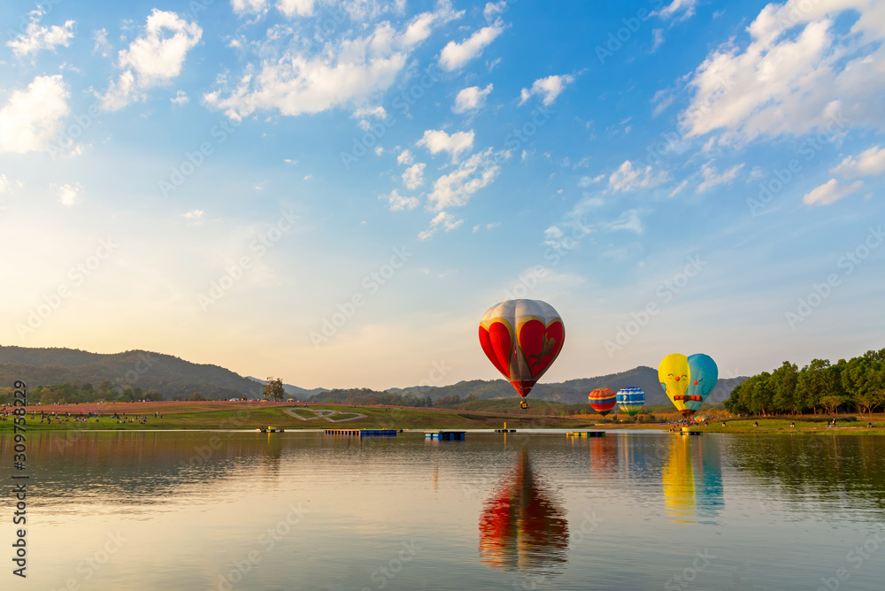 The hot air balloons flying over river and the cosmos flowers field in Chiang Rai province of Festival Thailand.