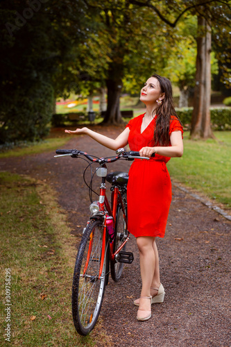 Beautiful girl in the rain riding a bicycle and admiring the beauty of nature