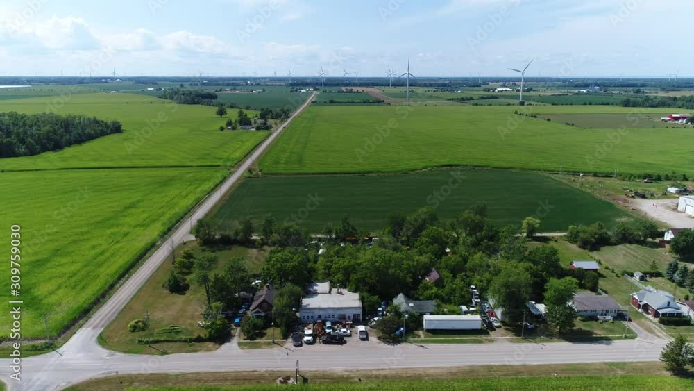 Sideways Aerial Energy Windmills Blowing In Distance In Small Town Farming Community Green Fields Sideways Aerial Energy Windmills Blowing In Distance In Small Town Farming Community Green Fields