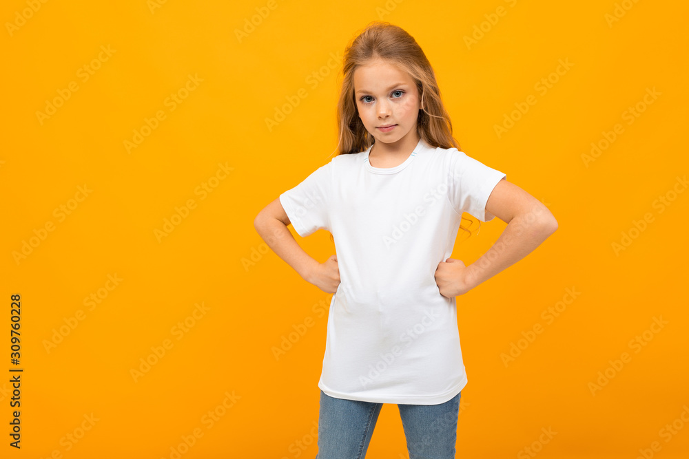 European cute girl in a white T-shirt with a mockup on a yellow wall European cute girl in a white T-shirt with a mockup on a yellow wall