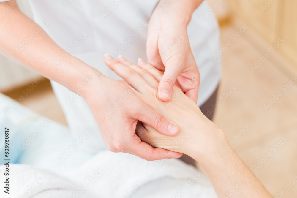 Close to the female hands of the masseur make a point massage of the hands in the cosmetology room.