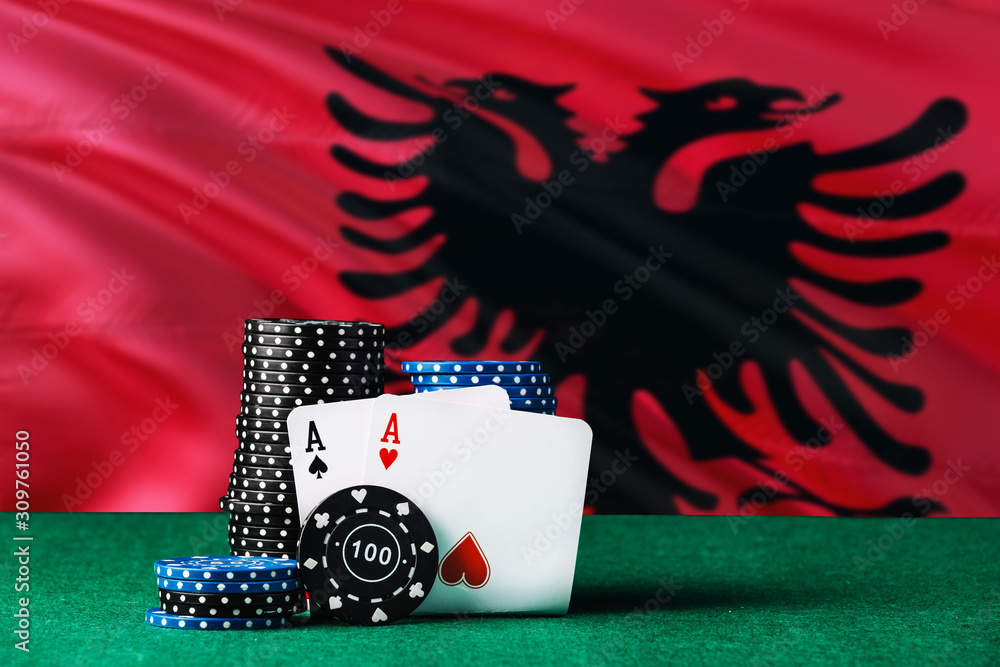 Albania casino theme. Two ace in poker game, cards and black chips on green table with national flag background. Gambling and betting.