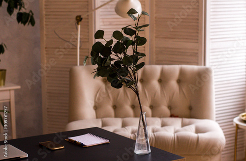 Loft style. Stylish scandinavian interior of living room with small design table and sofa. Beige walls, plants.