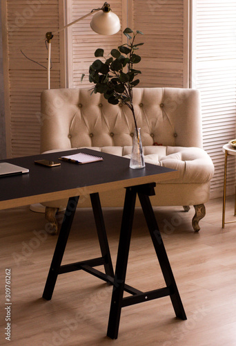 Loft style. Stylish scandinavian interior of living room with small design table and sofa. Beige walls, plants.